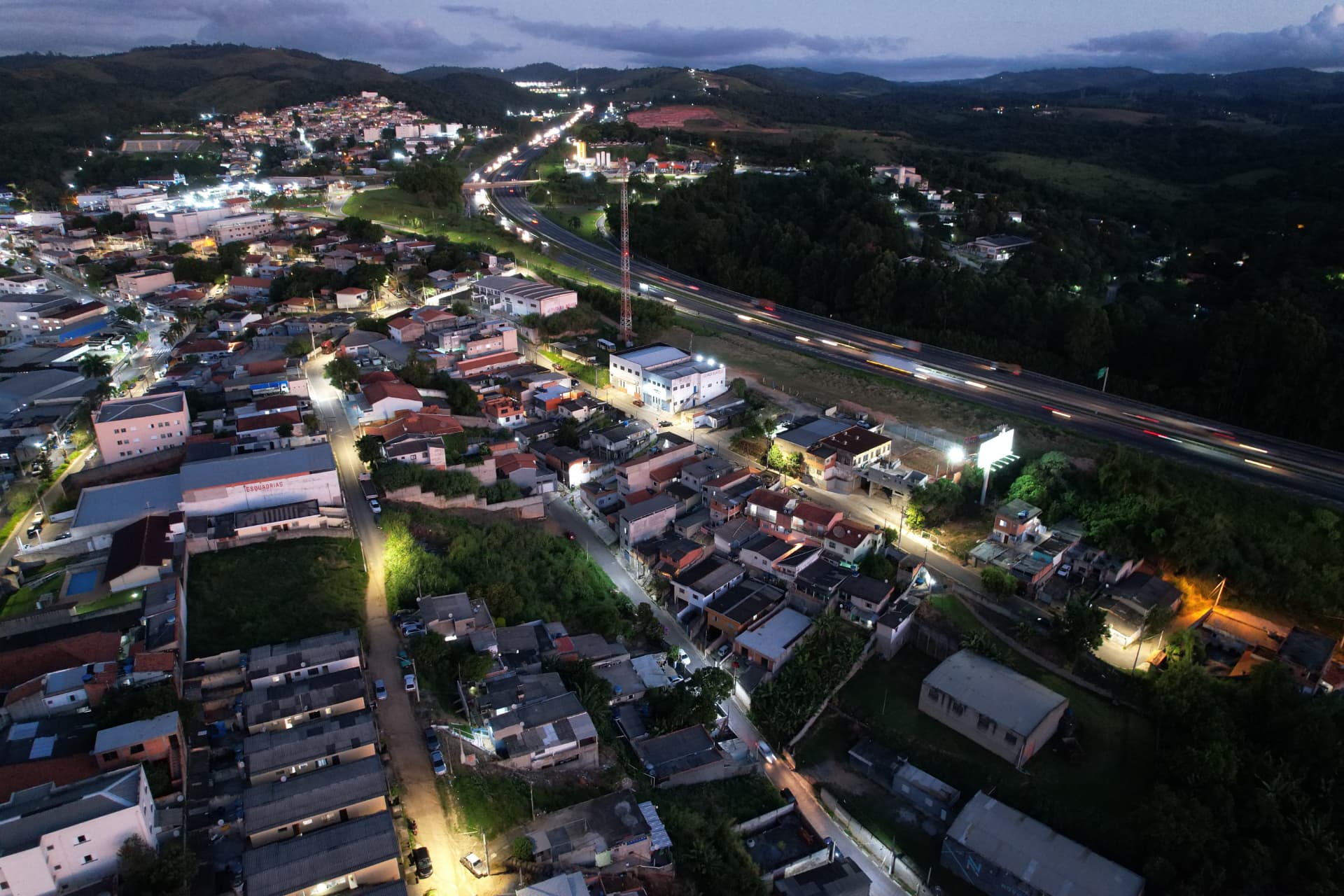 Imagem aérea noturna de cidade com estrada iluminada